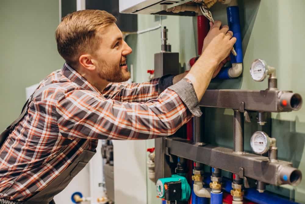 young gas engineer adjusting central heating system in london