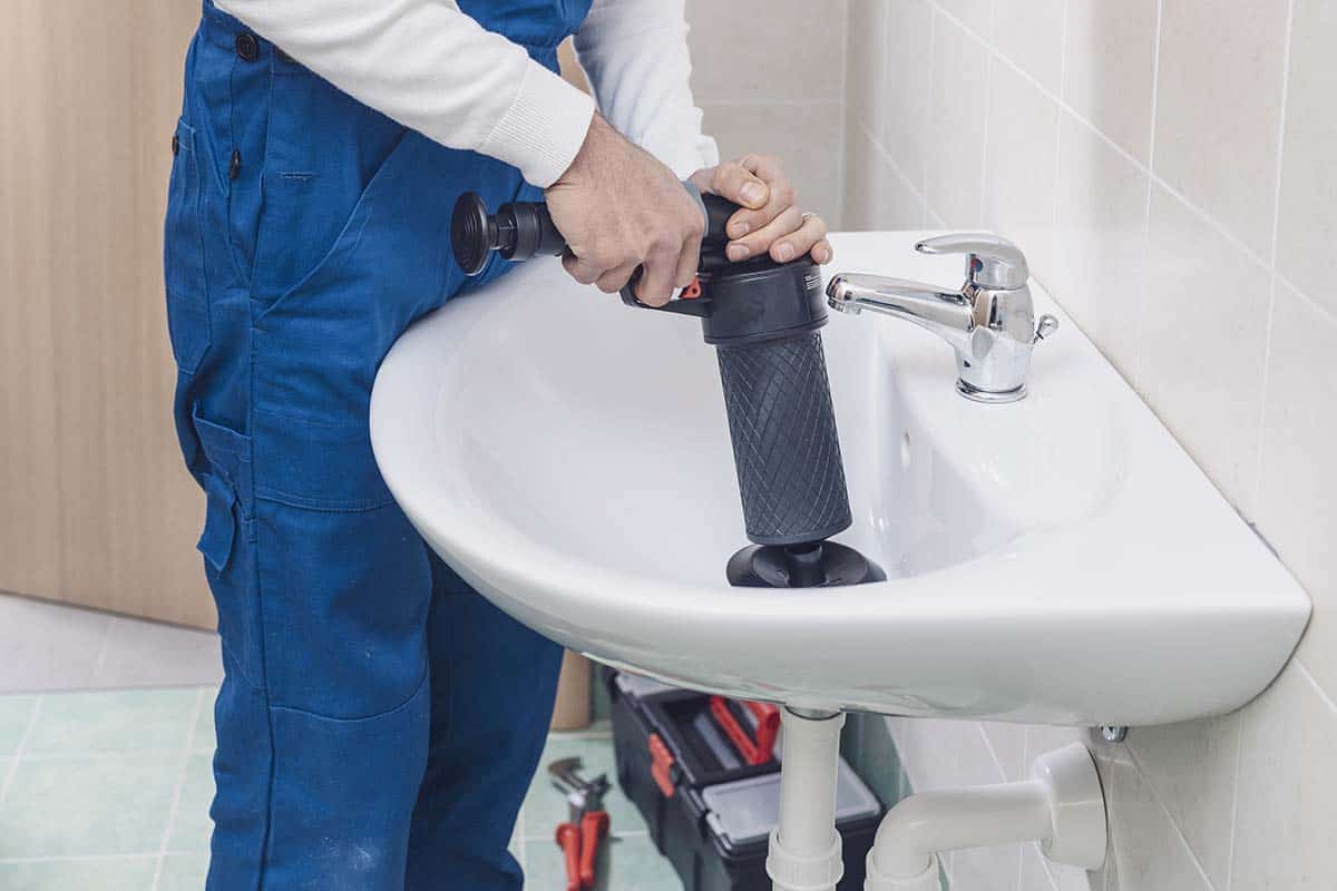 professional plumber unclogging a blocked sink in the bathroom